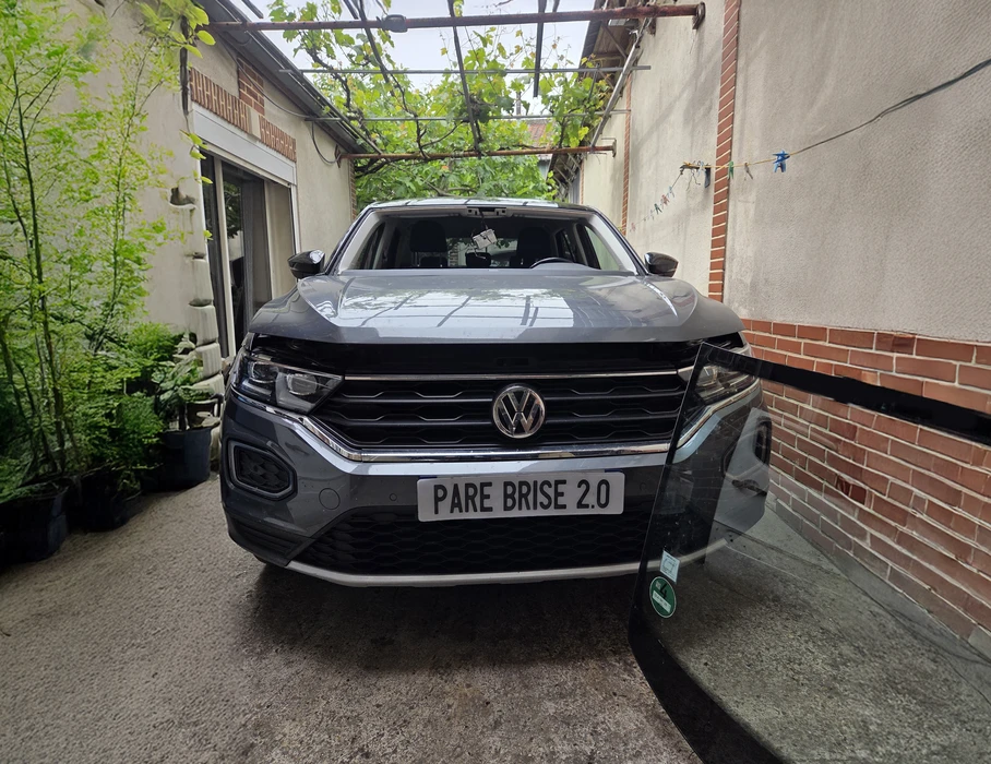 Atelier de carrosserie automobile avec véhicule Toyota blanc en cours de réparation. Environnement de garage professionnel avec murs en parpaings, sol béton et équipements techniques visibles.
