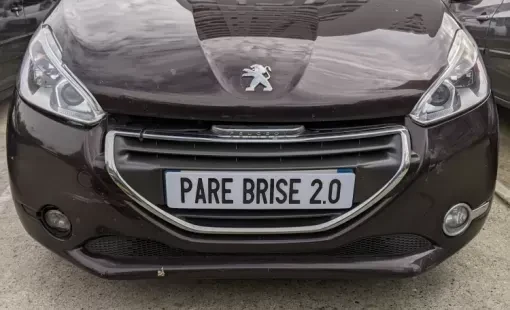 Voiture blanche sur route goudronnée au coucher du soleil. Véhicule moderne en mouvement avec éclairage naturel doré traversant le pare-brise et la carrosserie.